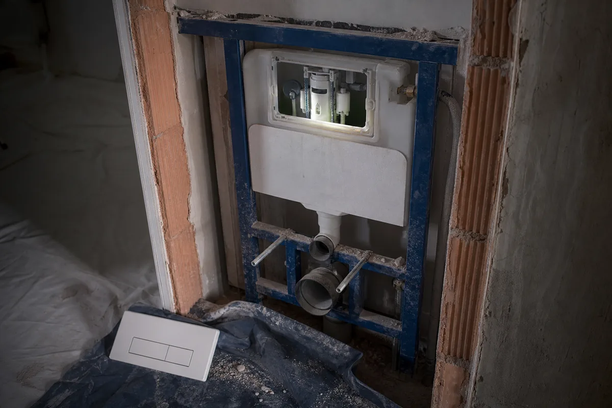 Bâti-support de WC suspendu ouvert dans une cloison de maison ancienne, mécanisme de chasse accessible